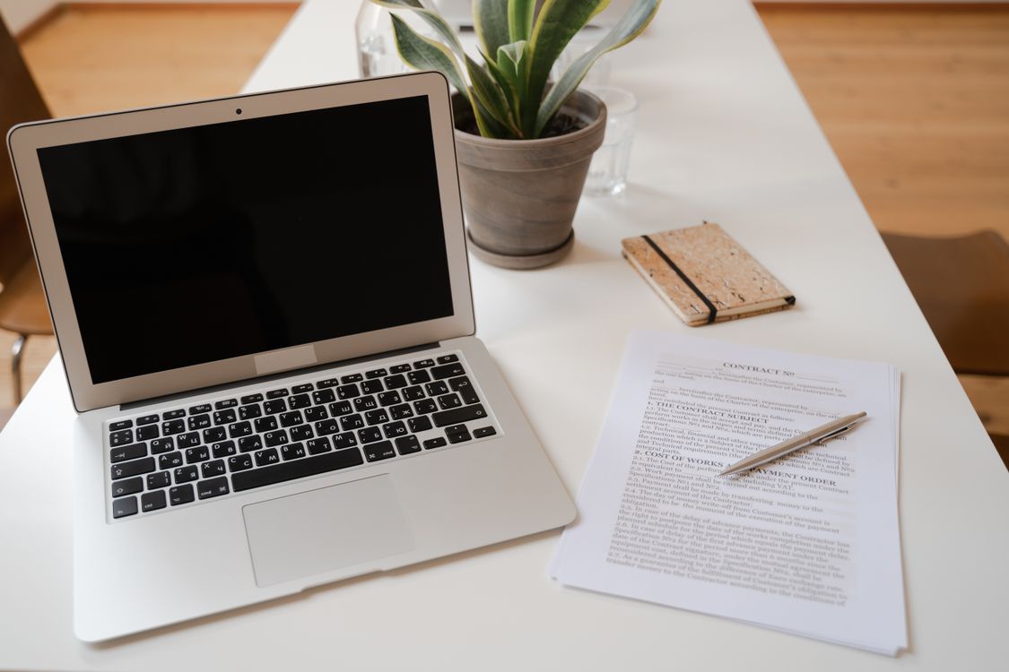 Laptop und Vertragsdokument mit Stift auf einem modernen Büroschreibtisch – professionelles Angebot schreiben