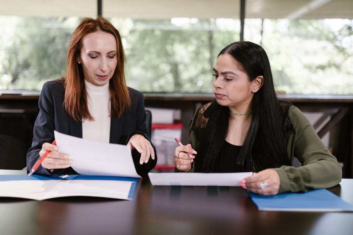 Zwei Geschäftsfrauen besprechen Angebots- und Vertragsunterlagen bei einem Meeting